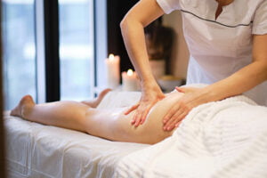 Masajista aplicando masaje reductor en piernas como técnica anticelulítica
